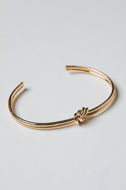 Gold bracelet on a light gray background