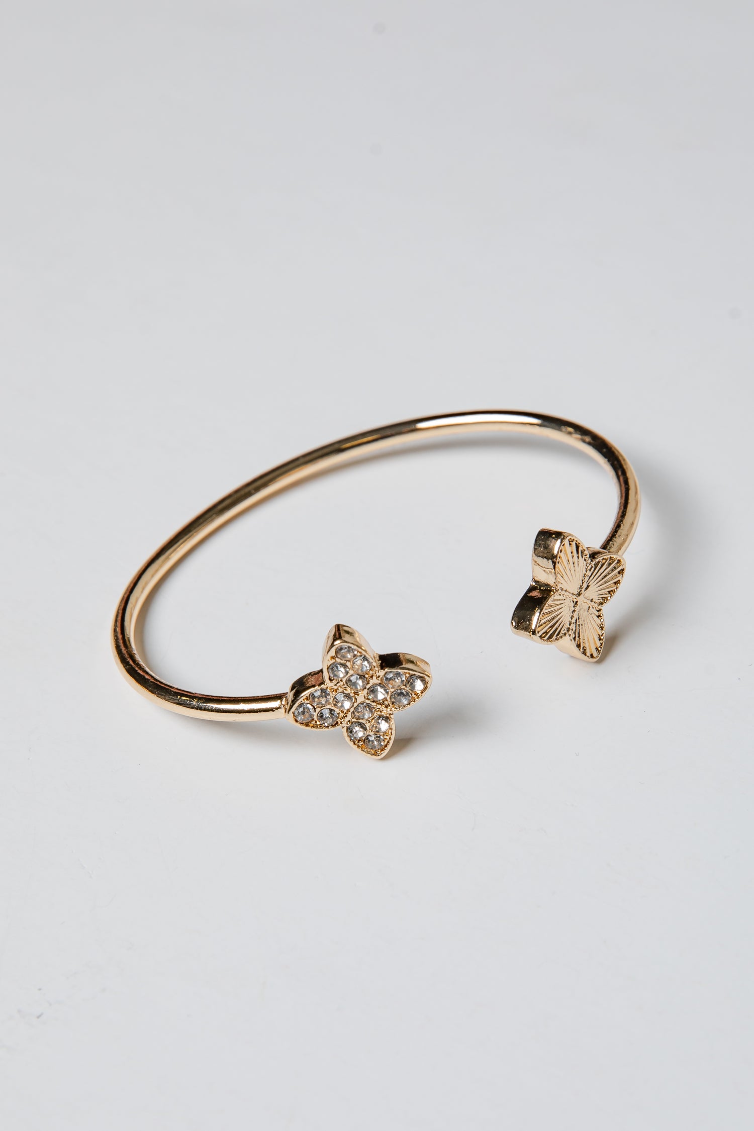 Gold bracelet with butterfly charms on a light gray background
