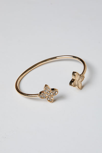 Gold bracelet with butterfly charms on a light gray background
