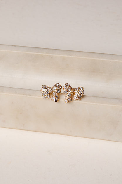 Rose gold bow-shaped earrings on a white surface