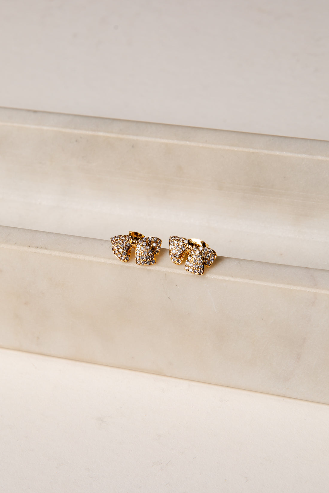 Gold earrings on a white surface