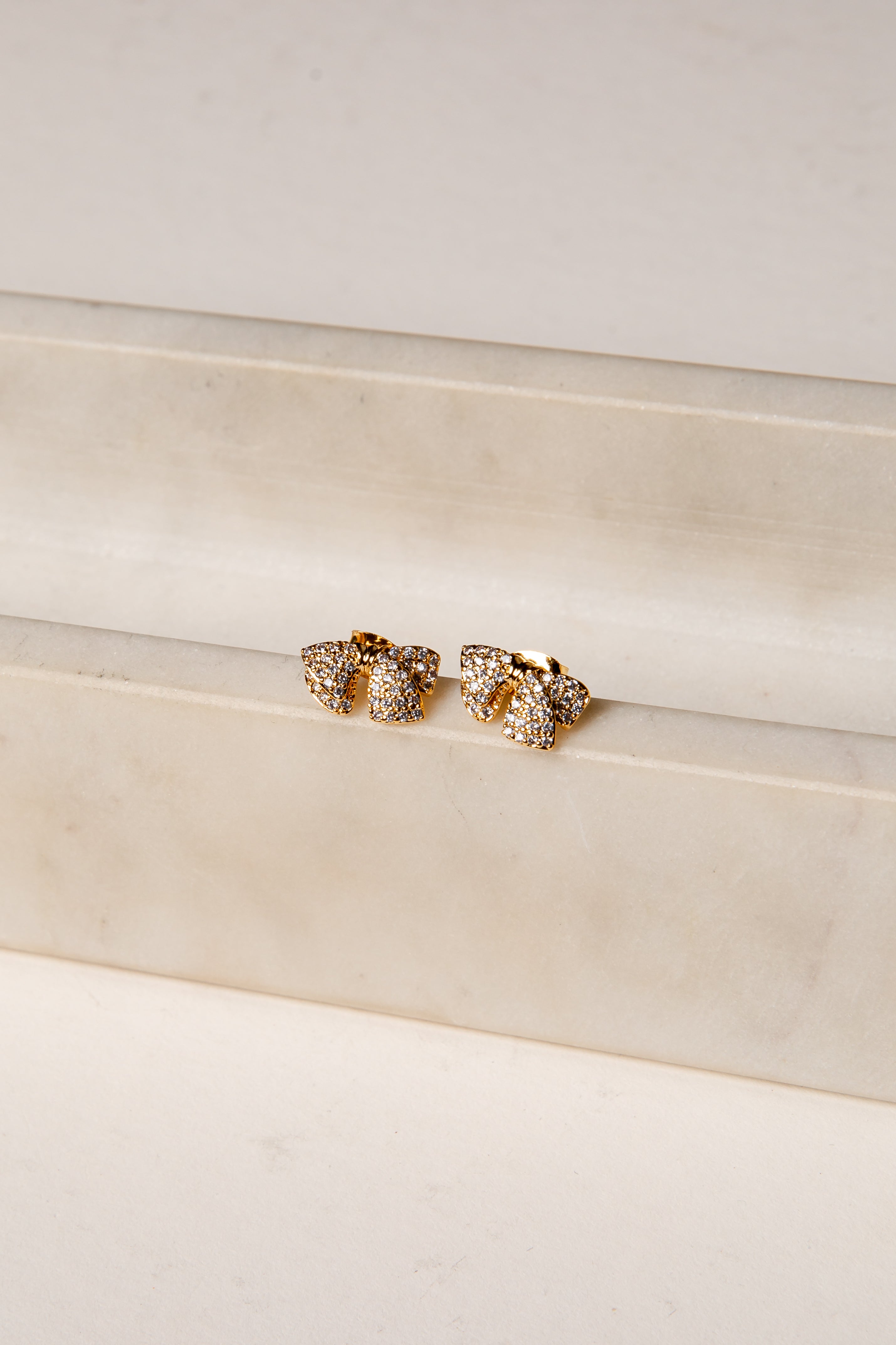Gold earrings on a white surface