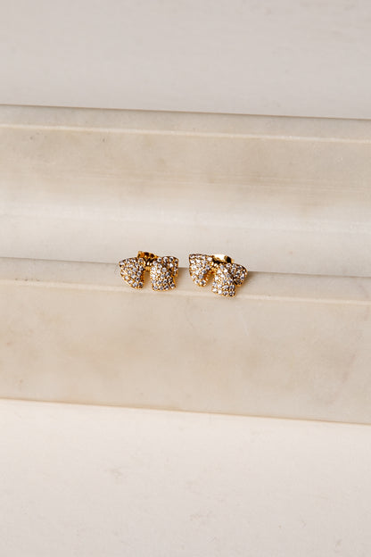 Gold earrings with clear stones on a beige fabric background