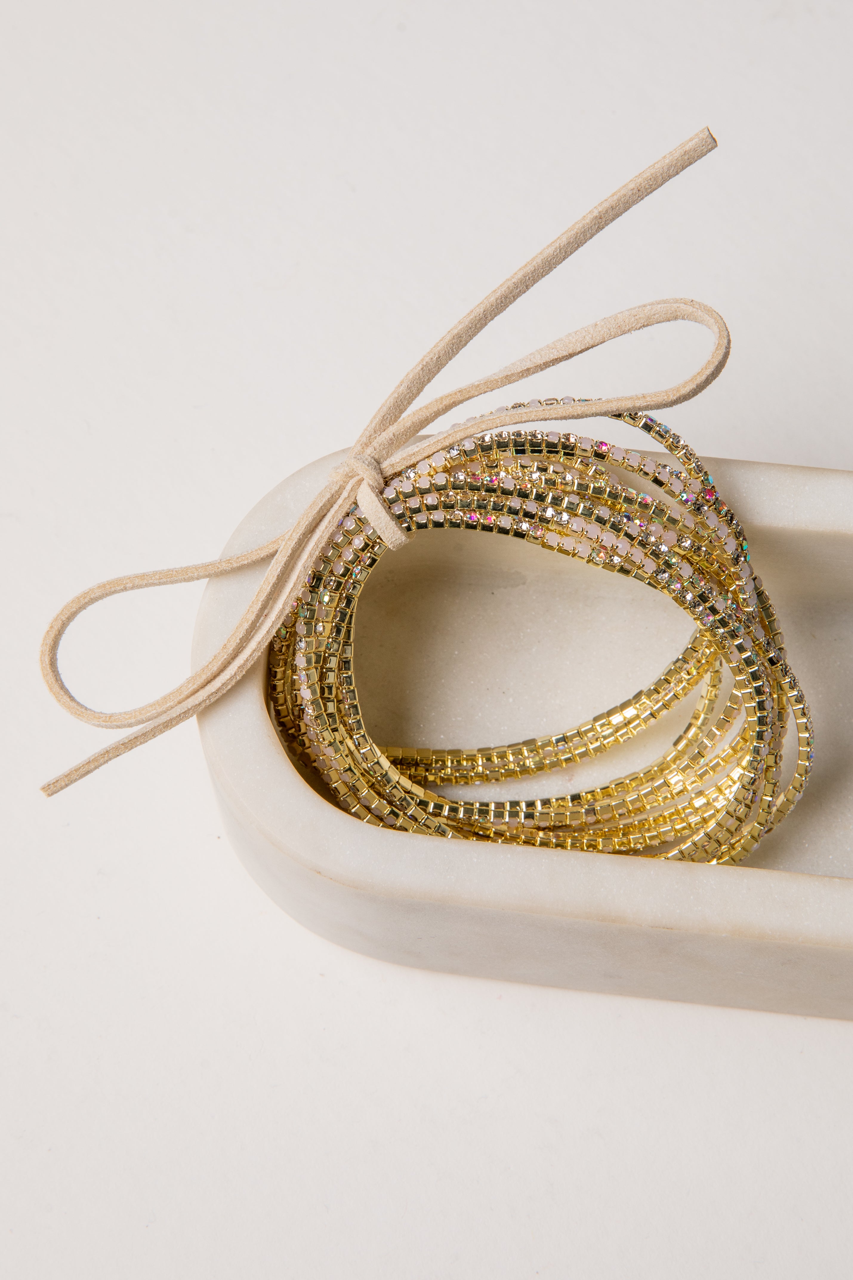 Gold beaded bracelets in a heart-shaped box on a light background