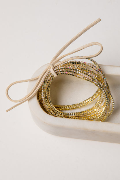 Gold beaded bracelets in a heart-shaped box on a light background