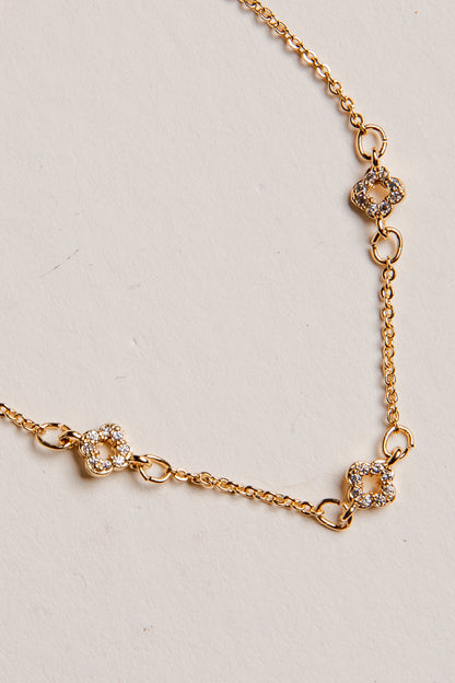 Gold necklace with floral links on a light gray background