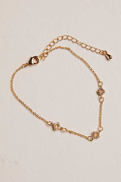 Gold bracelet with floral designs on a beige background