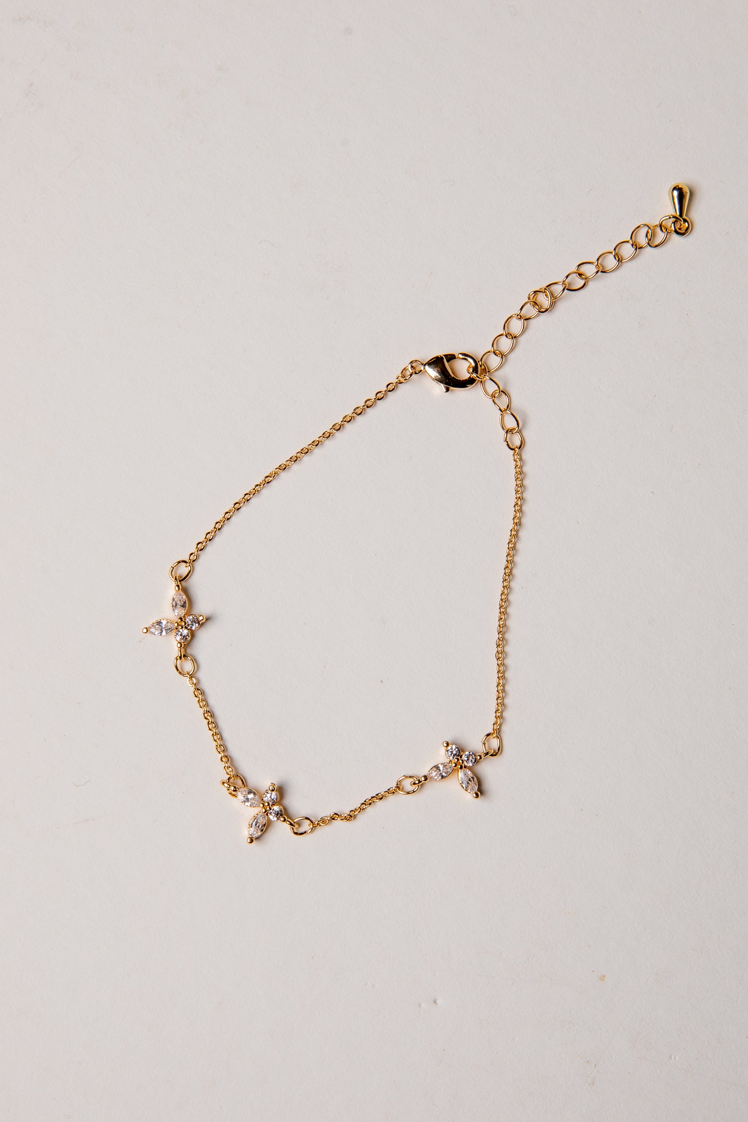 Gold bracelet with small charms on a light gray background