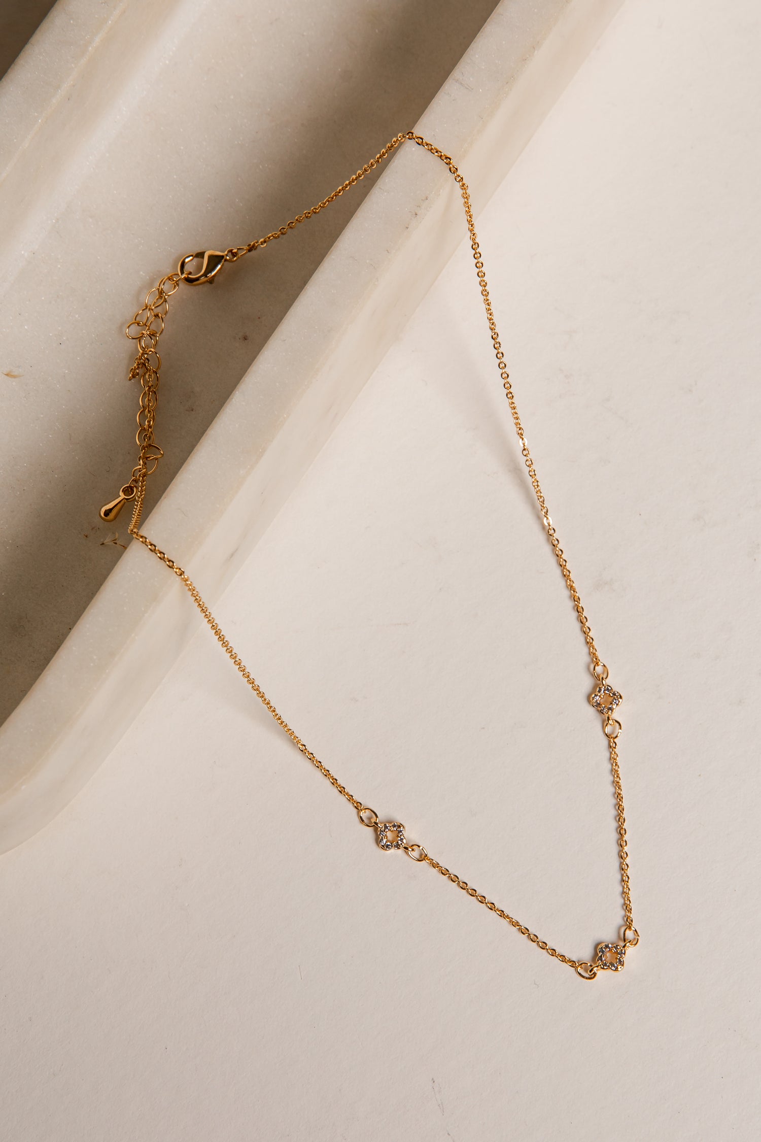 Gold necklace on a light beige surface