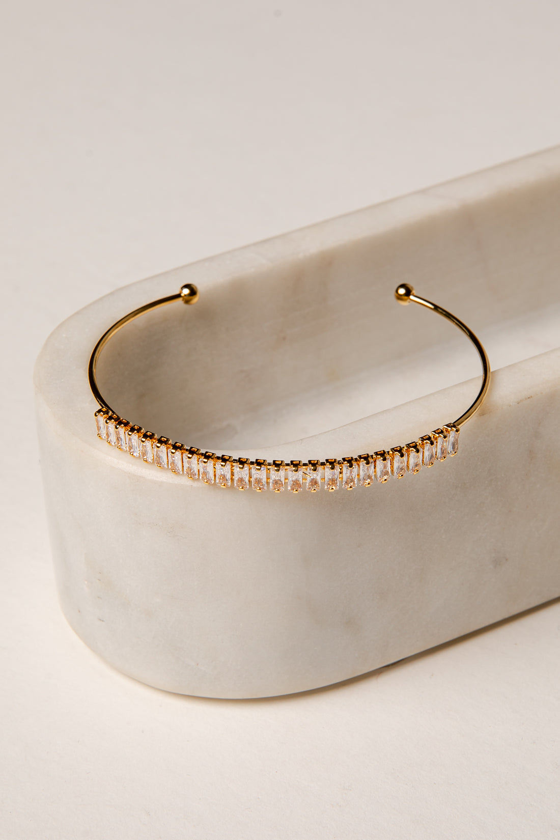 Gold hoop earring with embedded stones on a marble surface