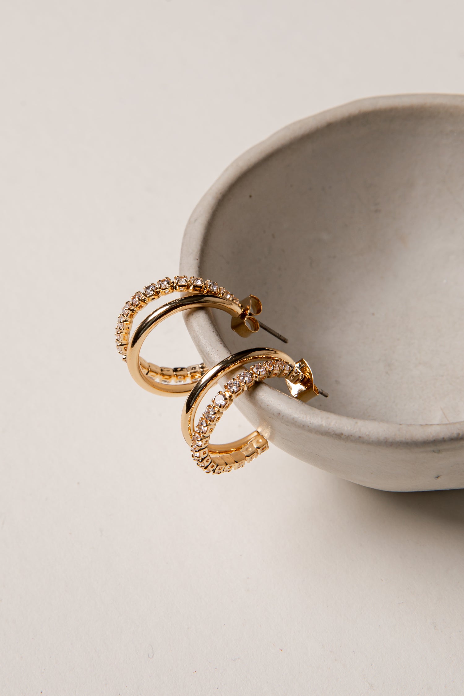 Gold hoop earrings on a light gray surface with a neutral background