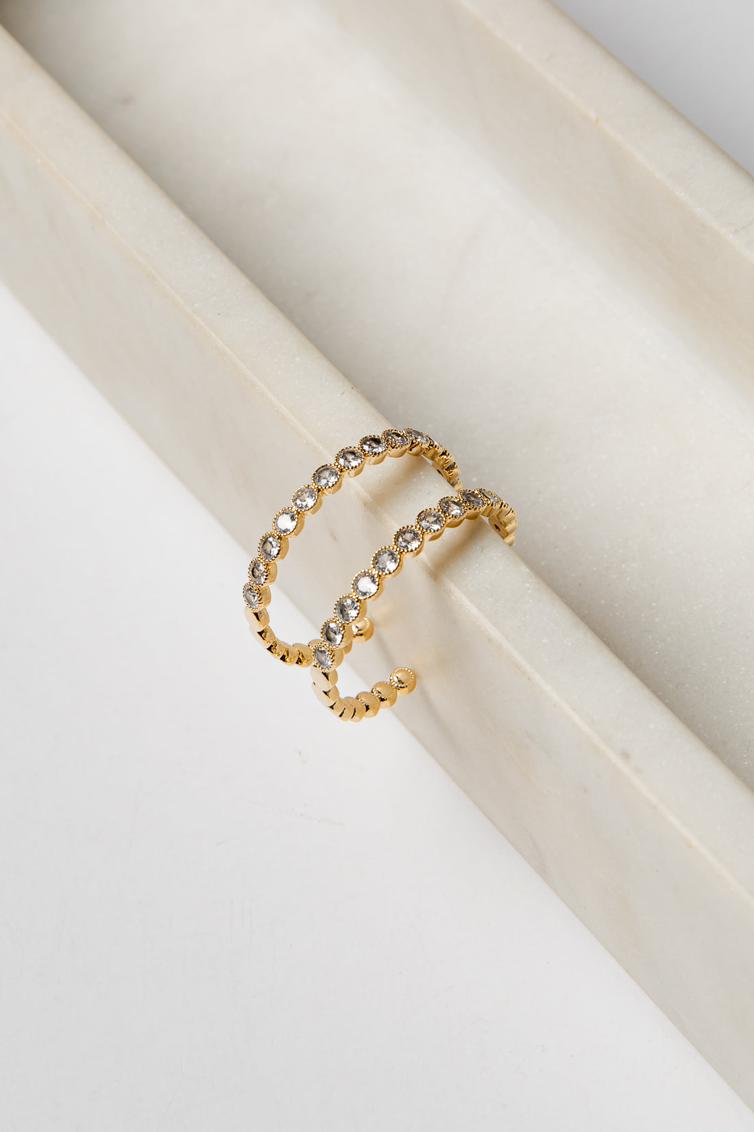 Gold earrings with embedded stones on a white surface