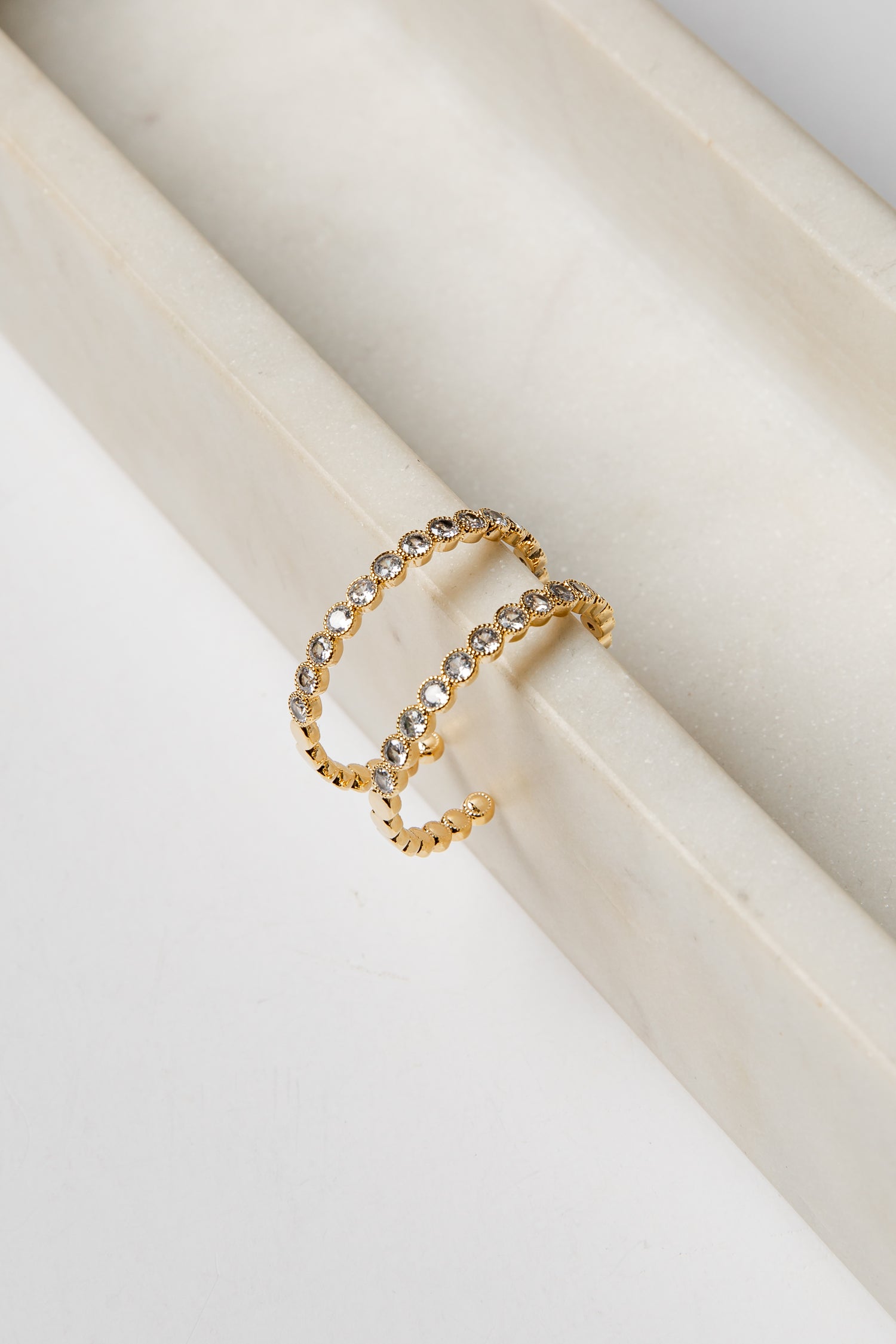 Gold earrings with embedded stones on a white surface