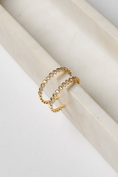 Gold earrings with embedded stones on a white surface