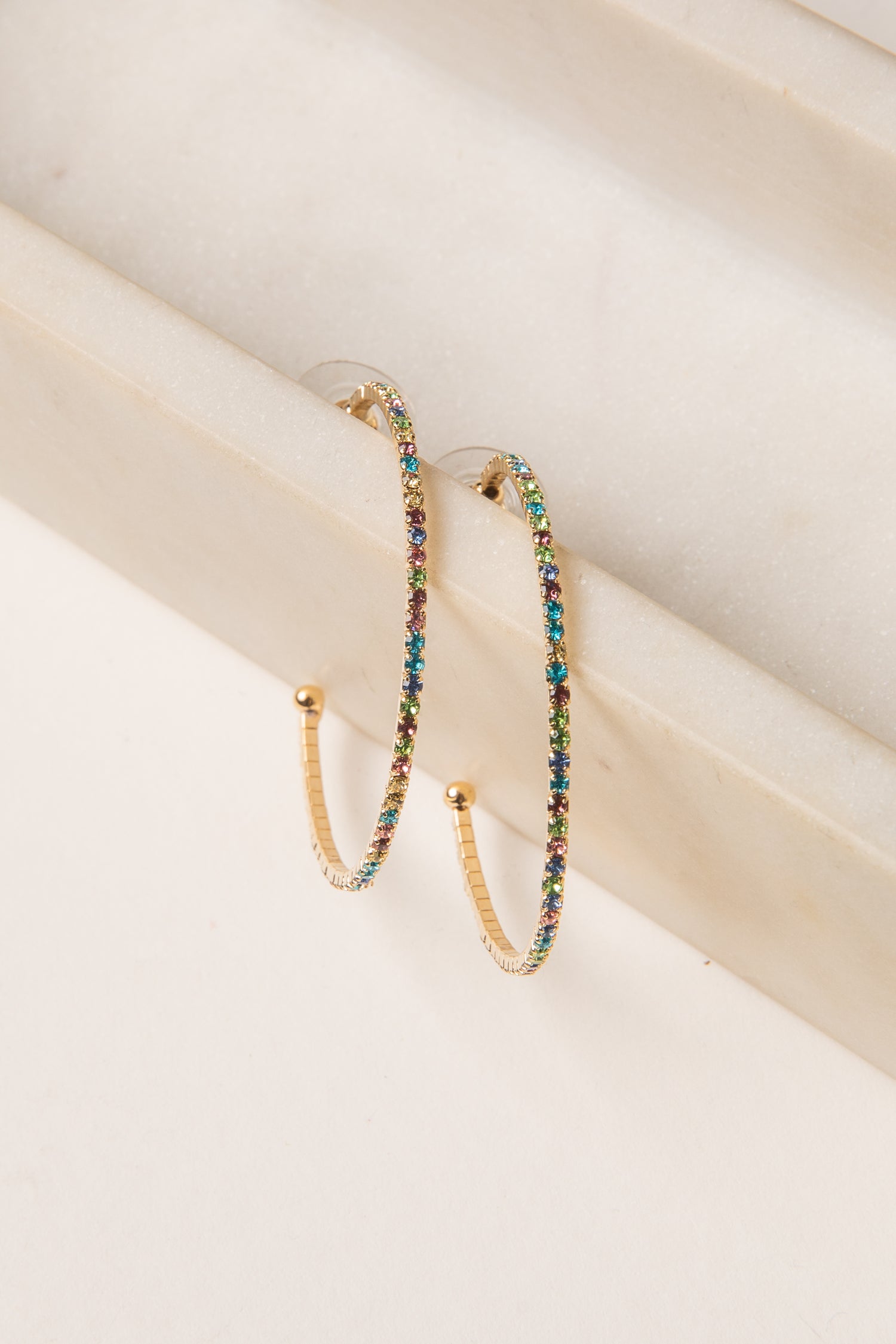 Multicolored beaded hoop earrings on a light wooden surface