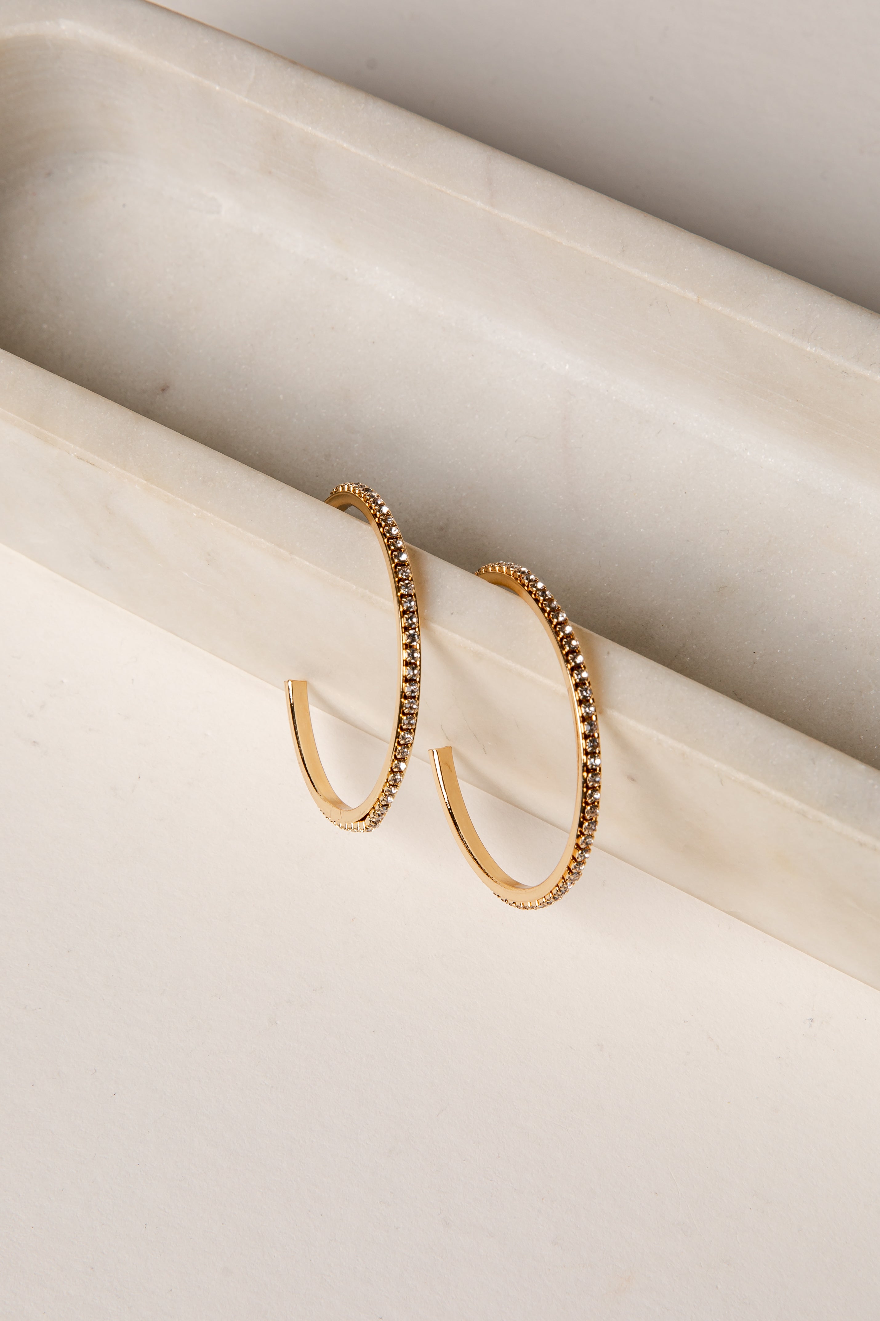 Gold hoop earrings on a light beige surface