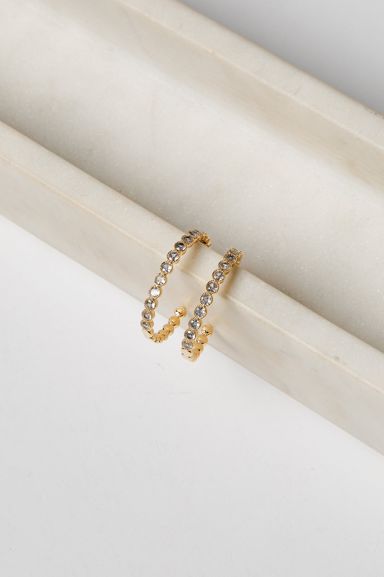 Gold earrings with embedded stones on a white surface