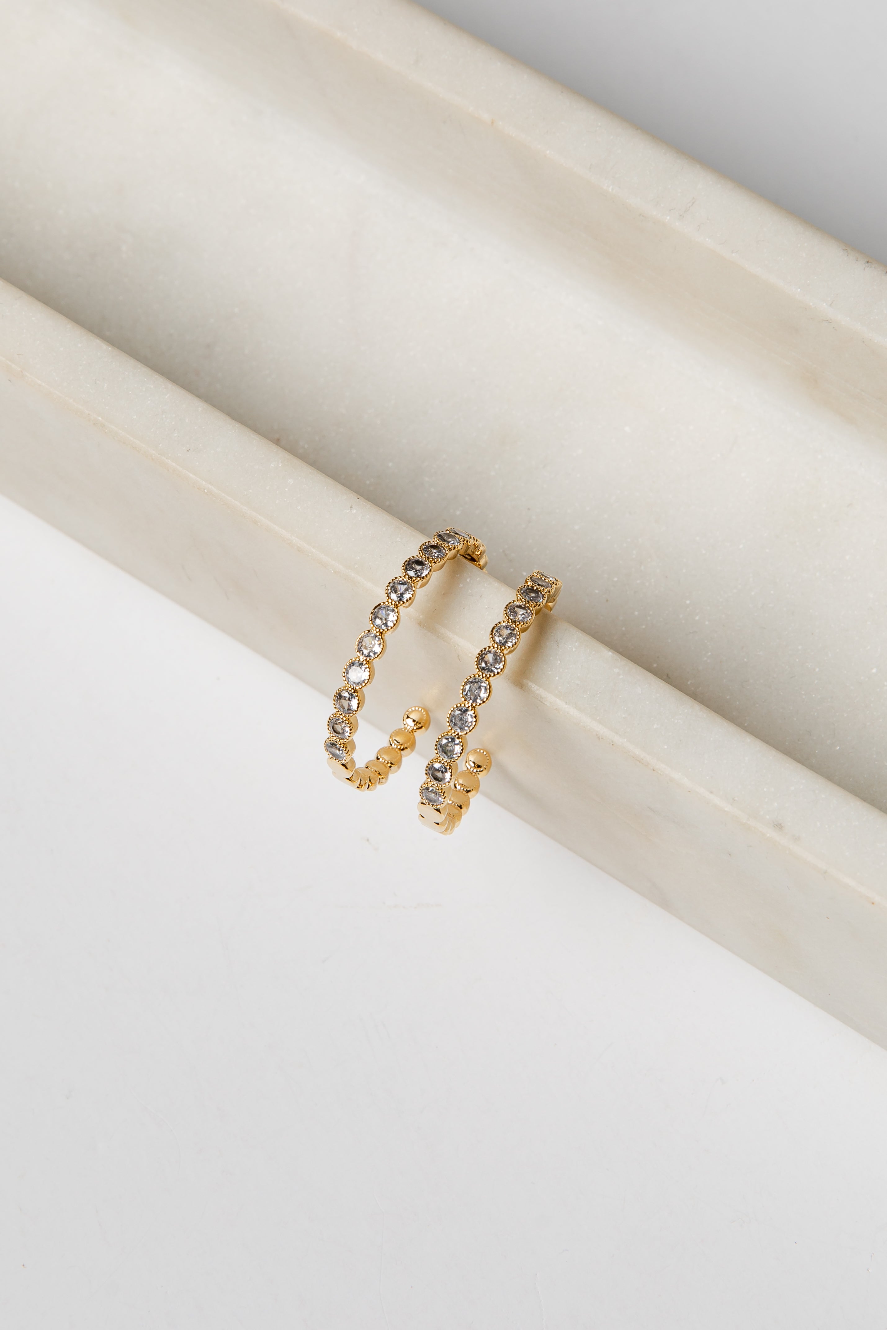 Gold earrings with embedded stones on a white surface