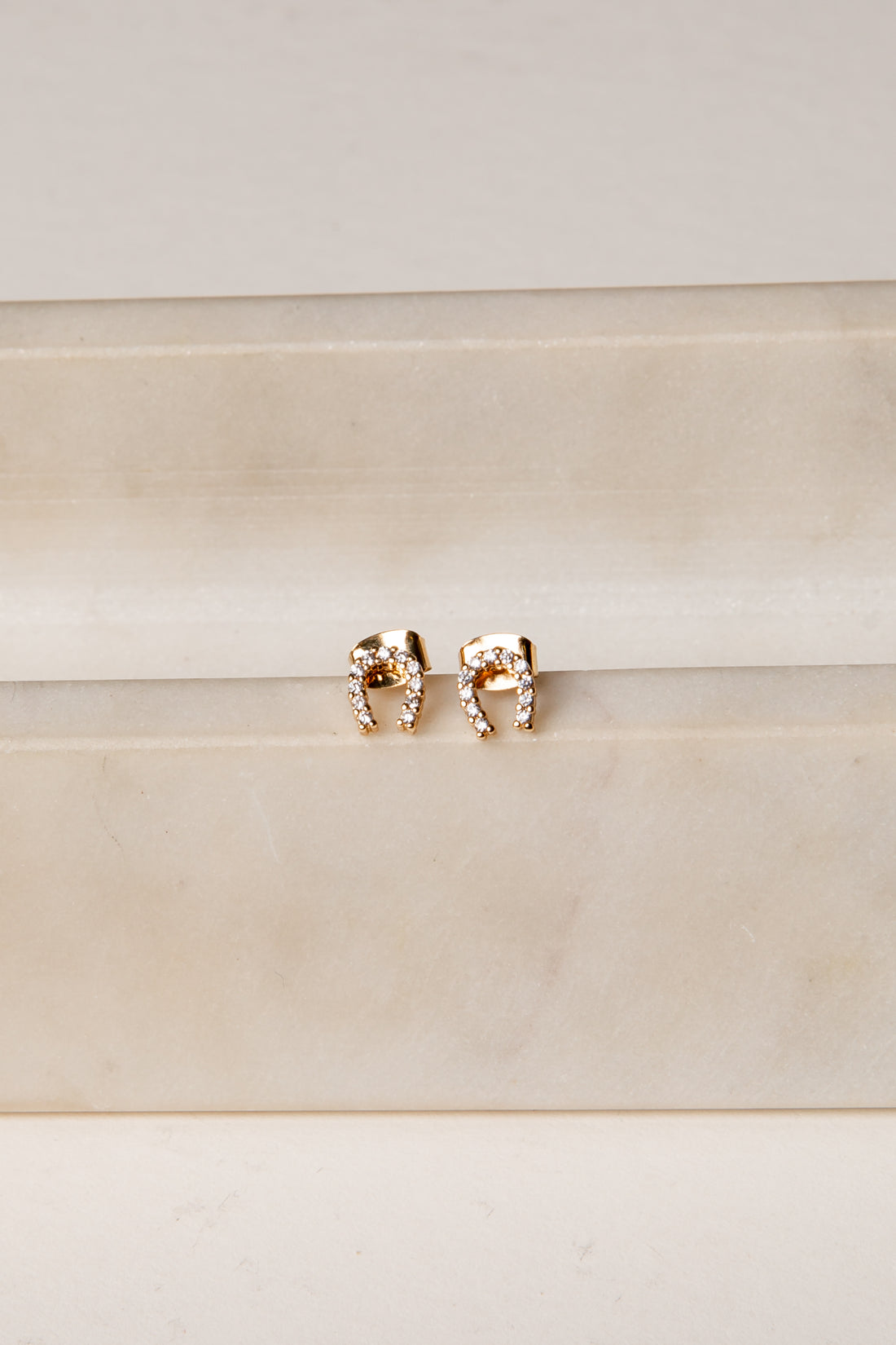 Rose gold elephant earrings on a beige background