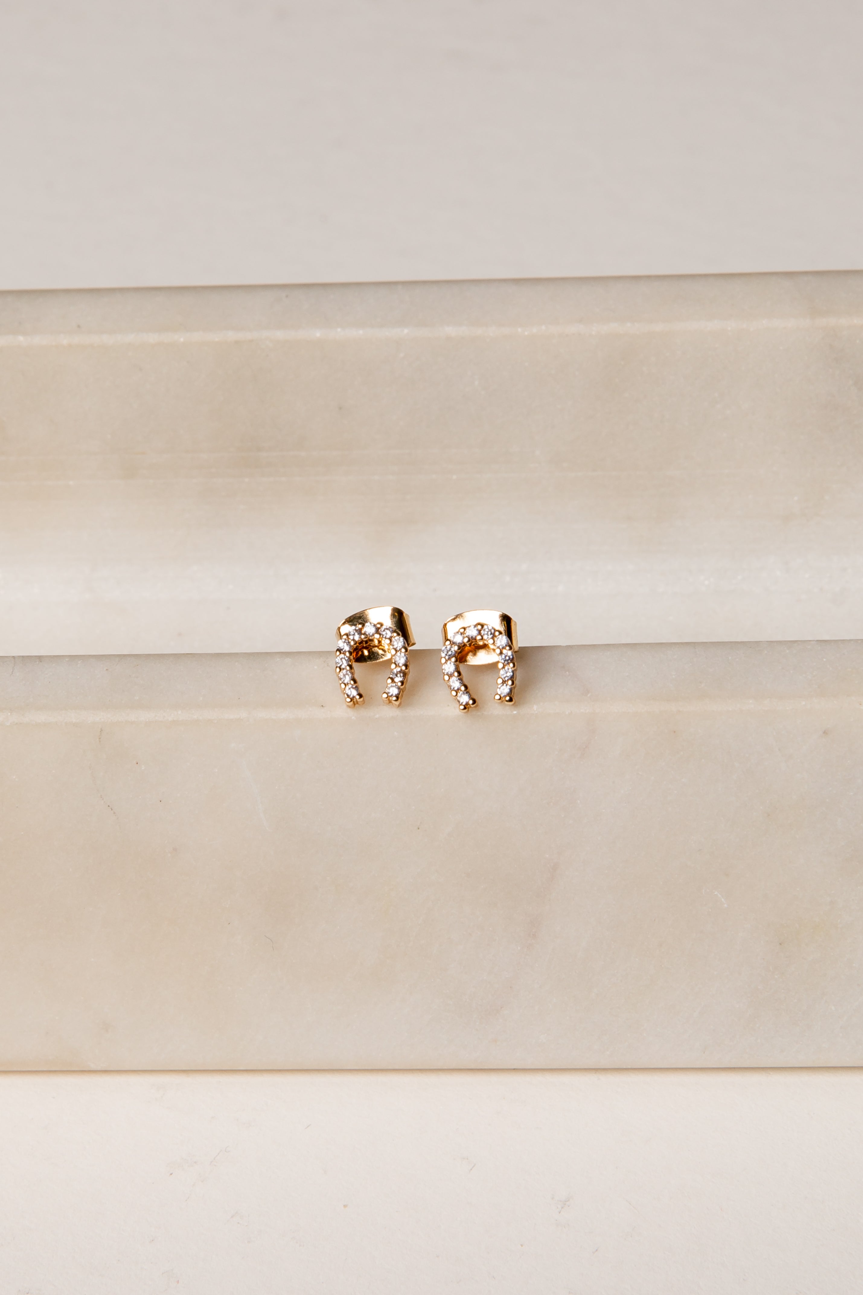 Rose gold elephant earrings on a beige background