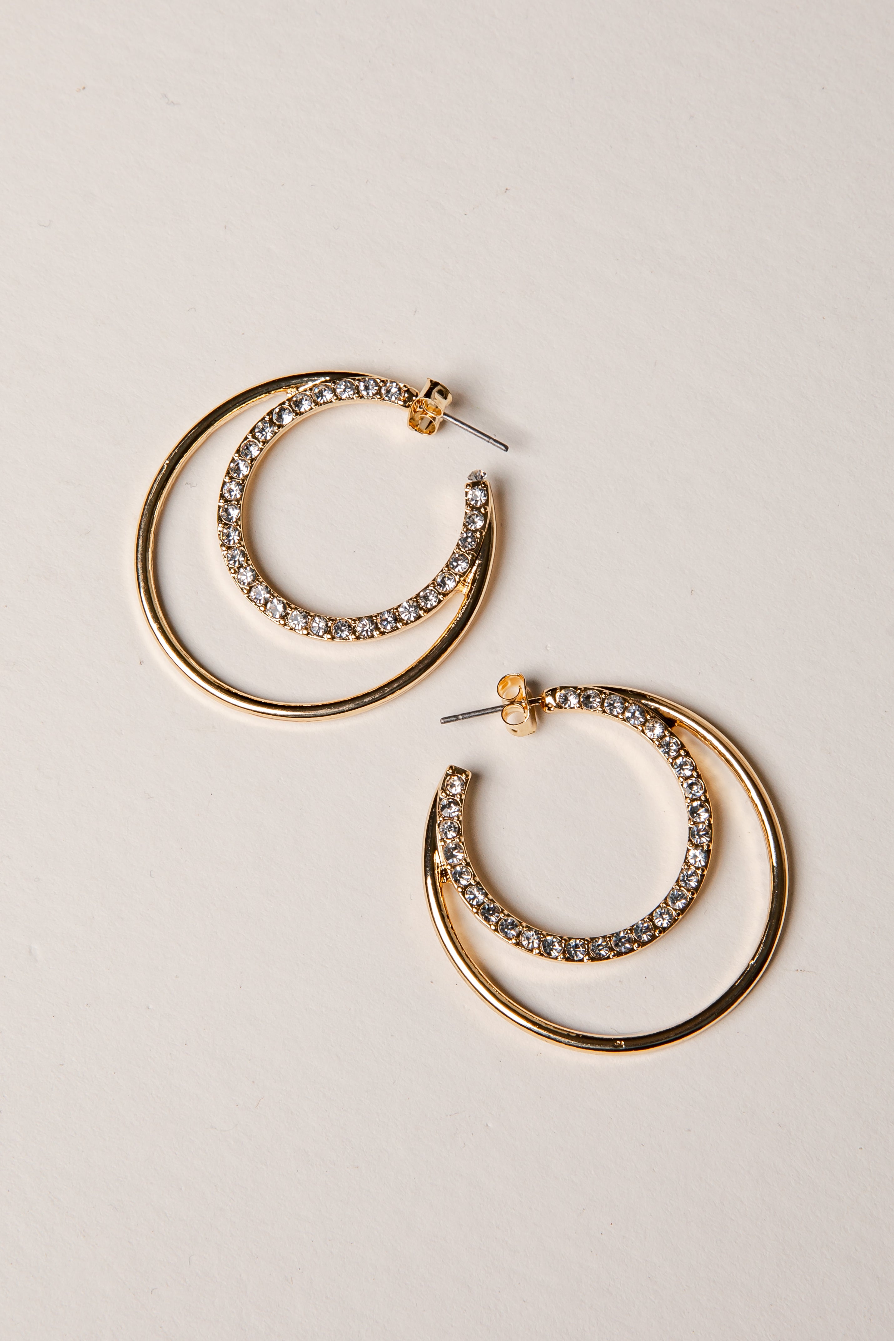 Gold hoop earrings with gemstones on a beige background