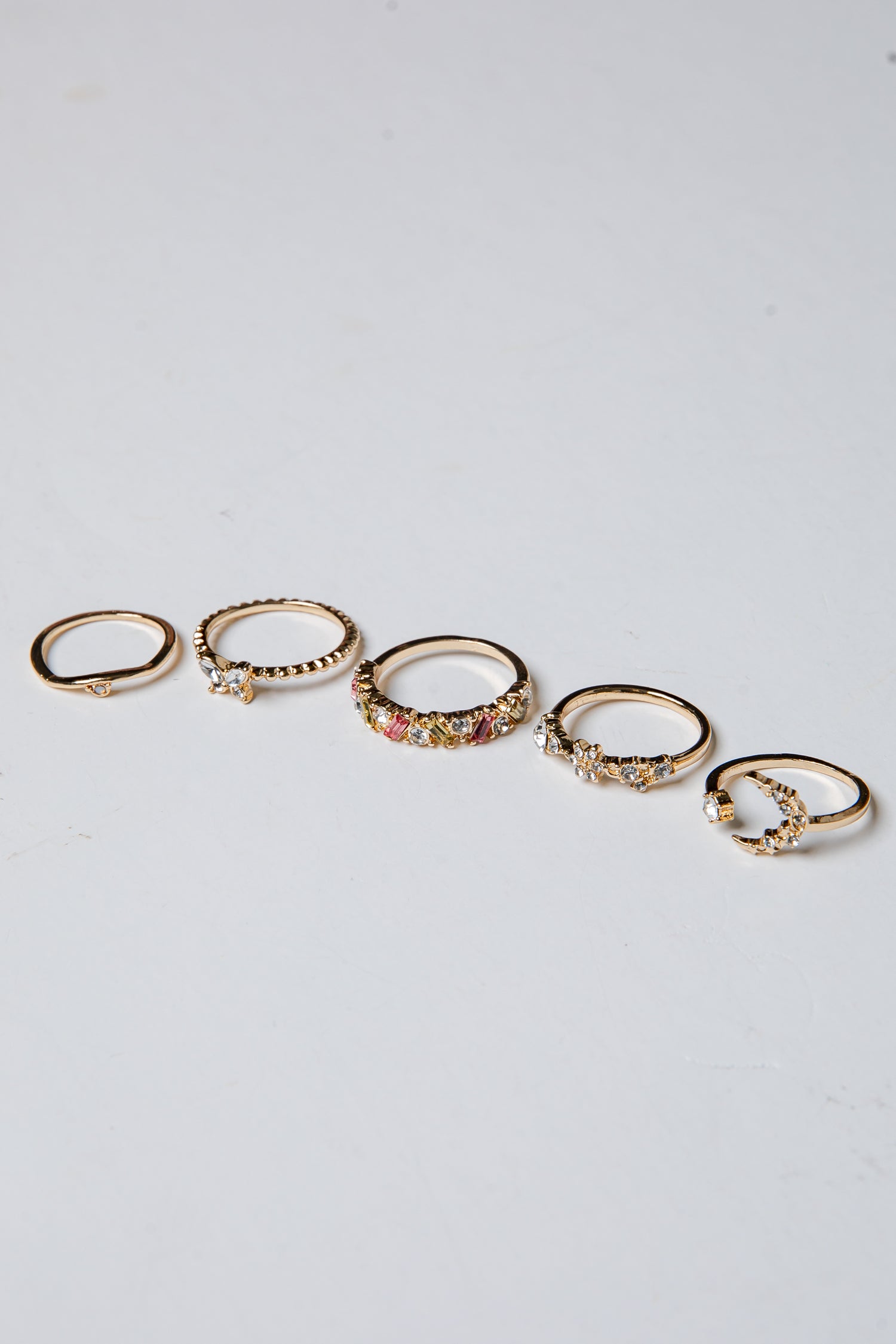 Set of gold rings with small stones on a light gray background