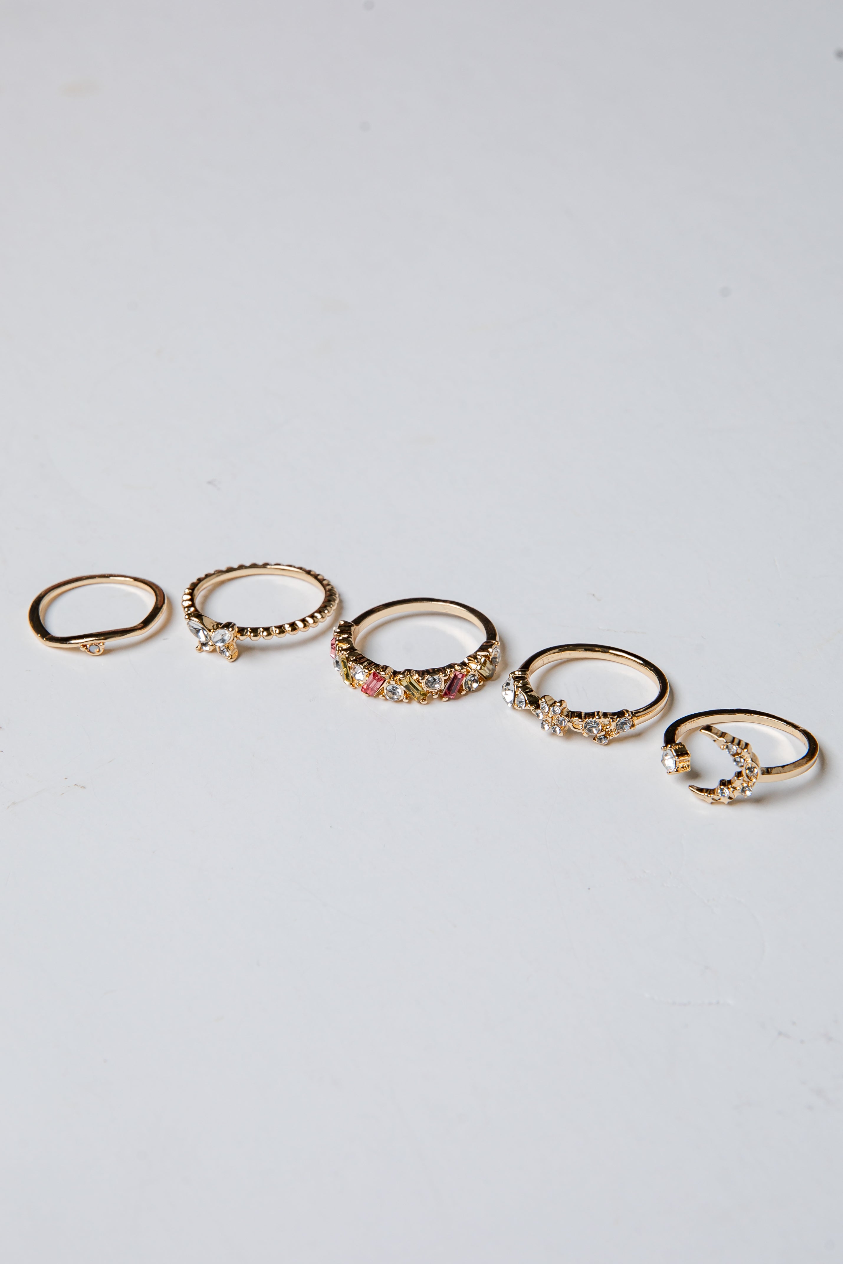 Set of gold rings with small stones on a light gray background