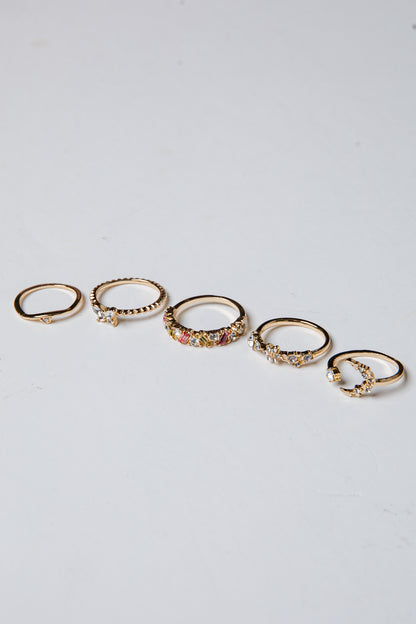 Set of gold rings with small stones on a light gray background