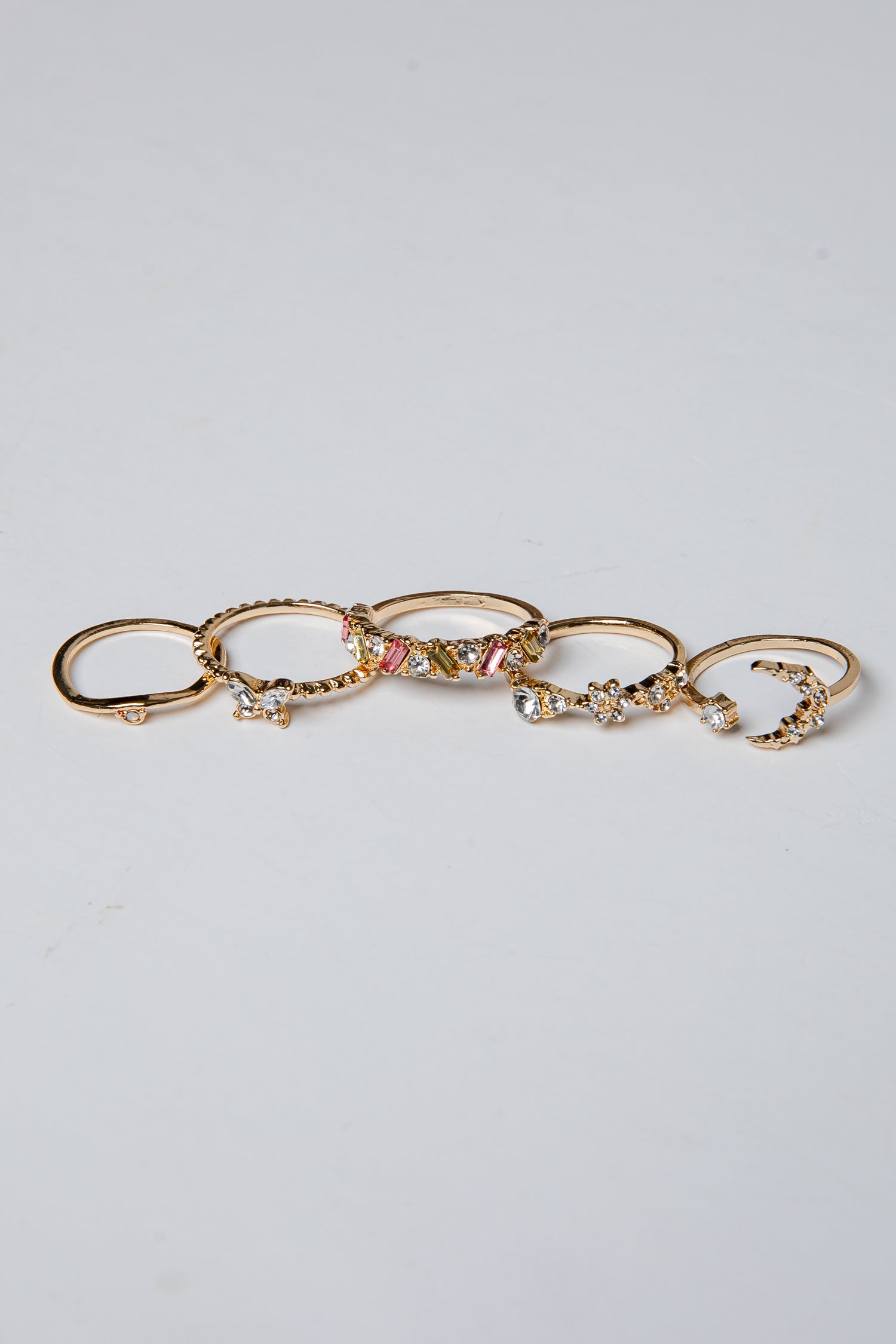 Set of gold rings with various designs on a light gray background