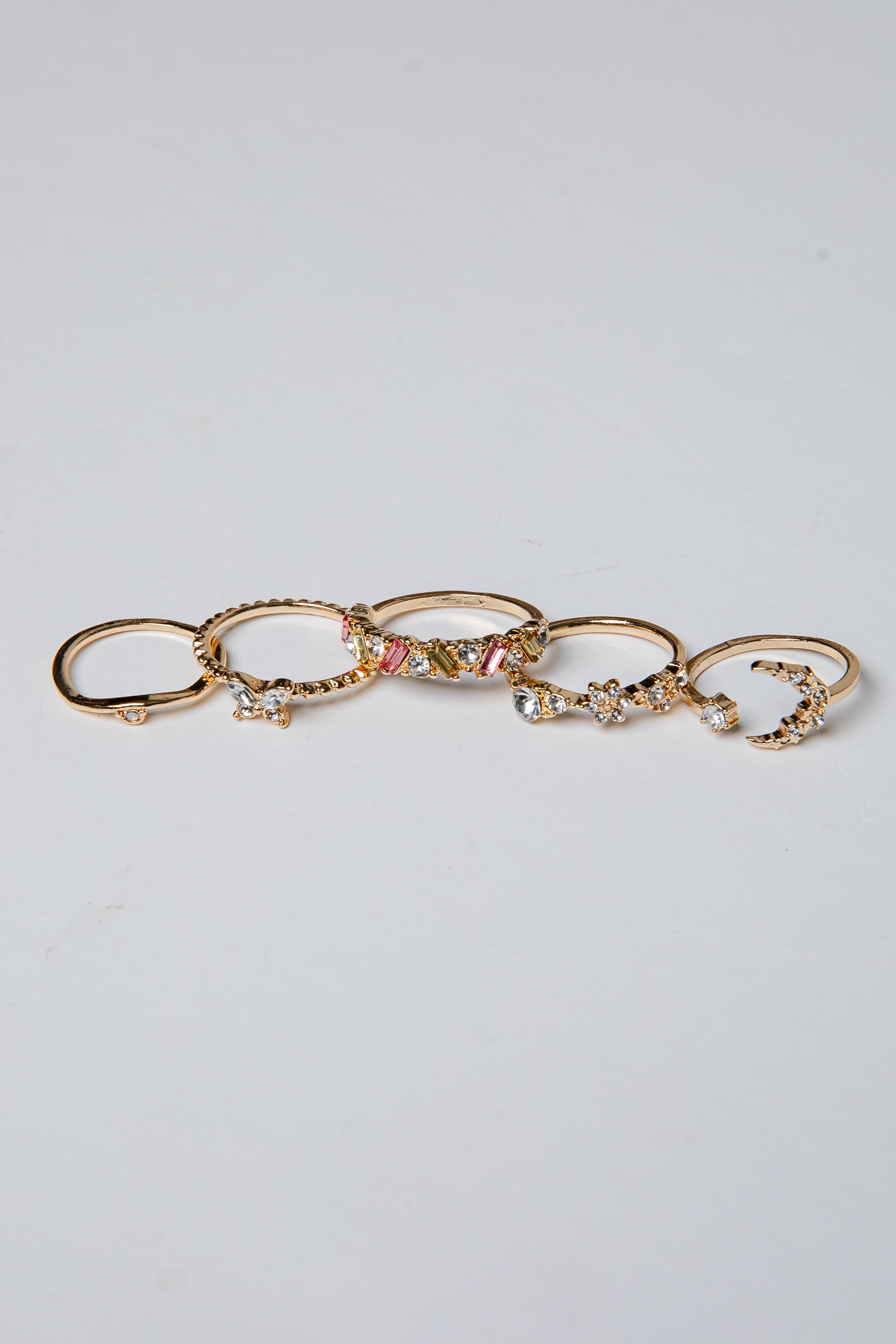 Set of gold rings with various designs on a light gray background