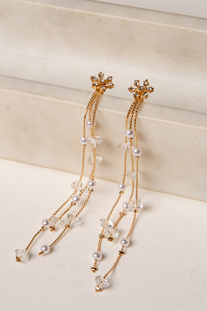 Gold and pearl earrings on a light beige background