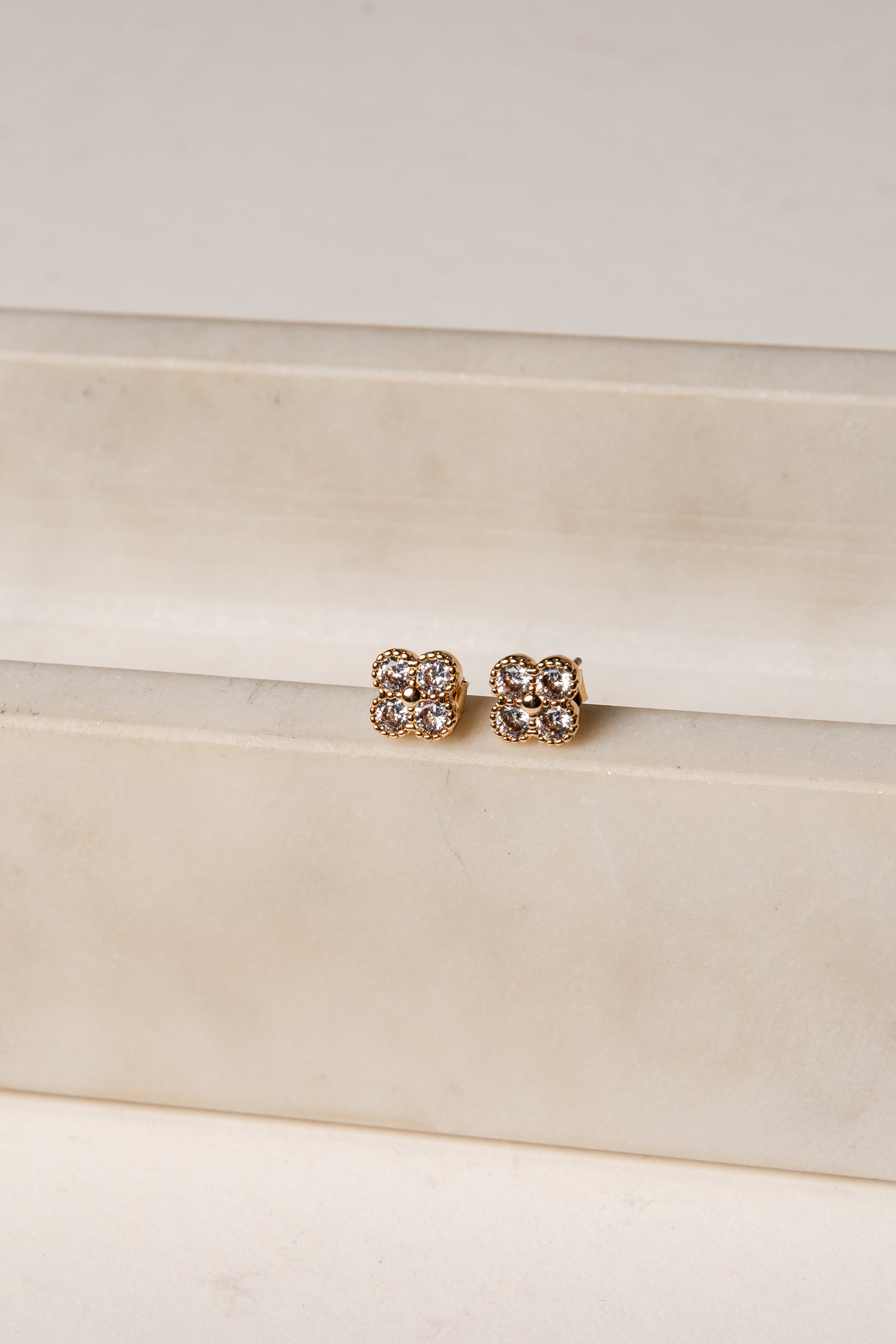 Pair of gold earrings on a white satin surface