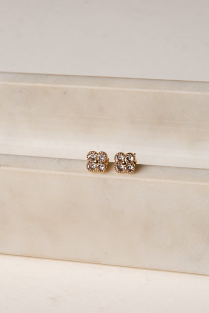 Pair of gold earrings on a white satin surface