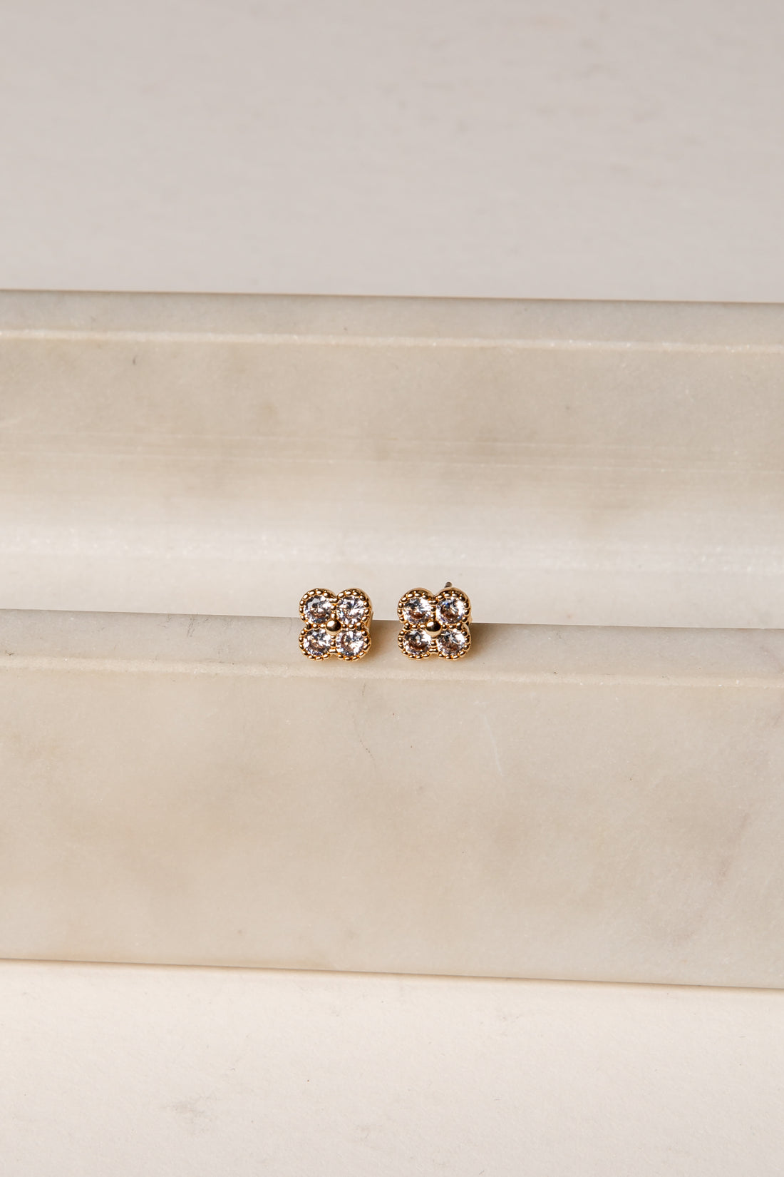 Pair of gold earrings with clear stones on a white background
