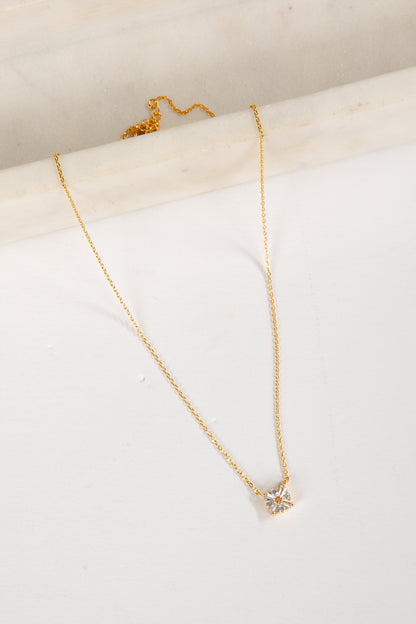 Gold necklace with a star-shaped pendant on a white surface