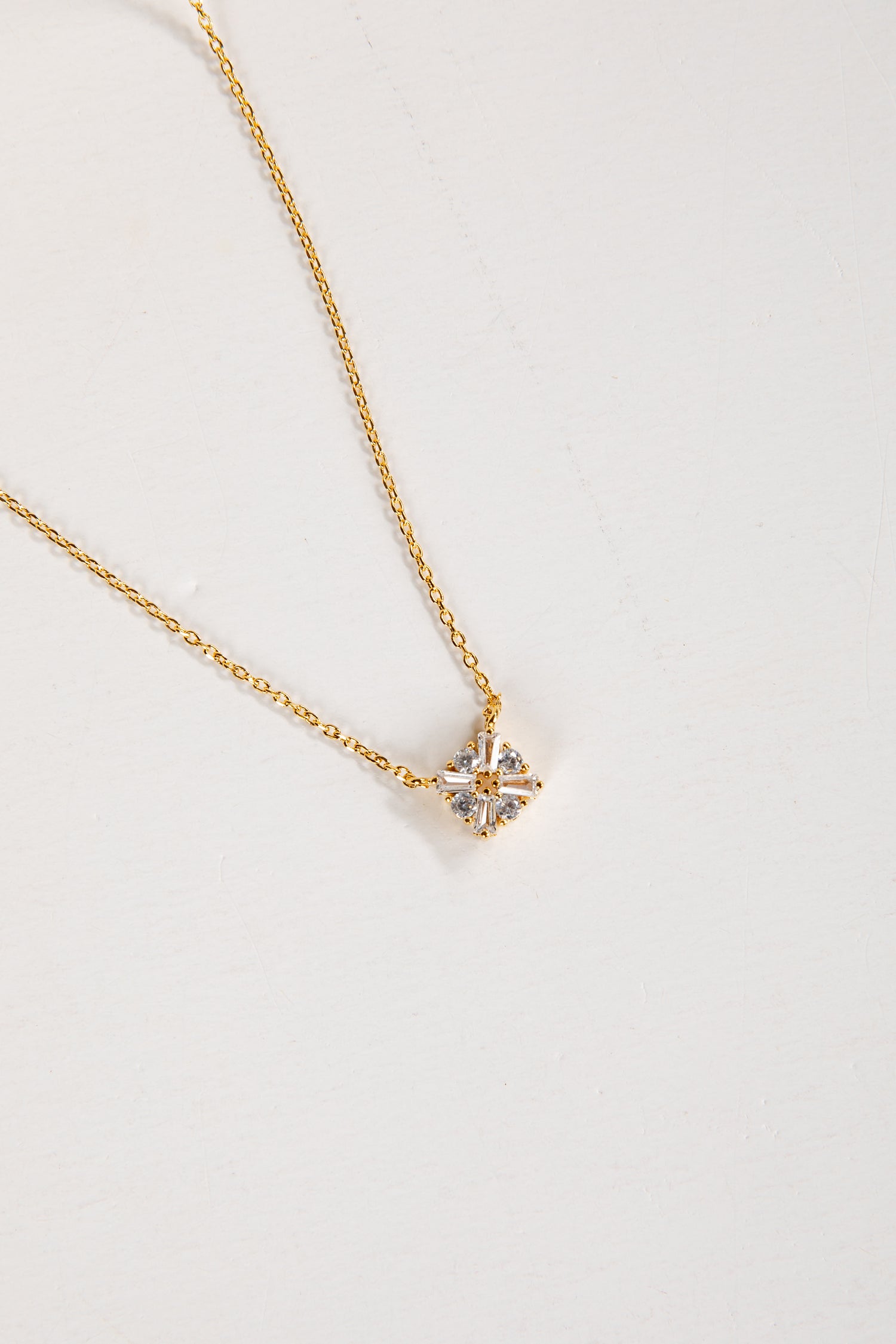 Gold necklace with a star-shaped pendant on a light gray background