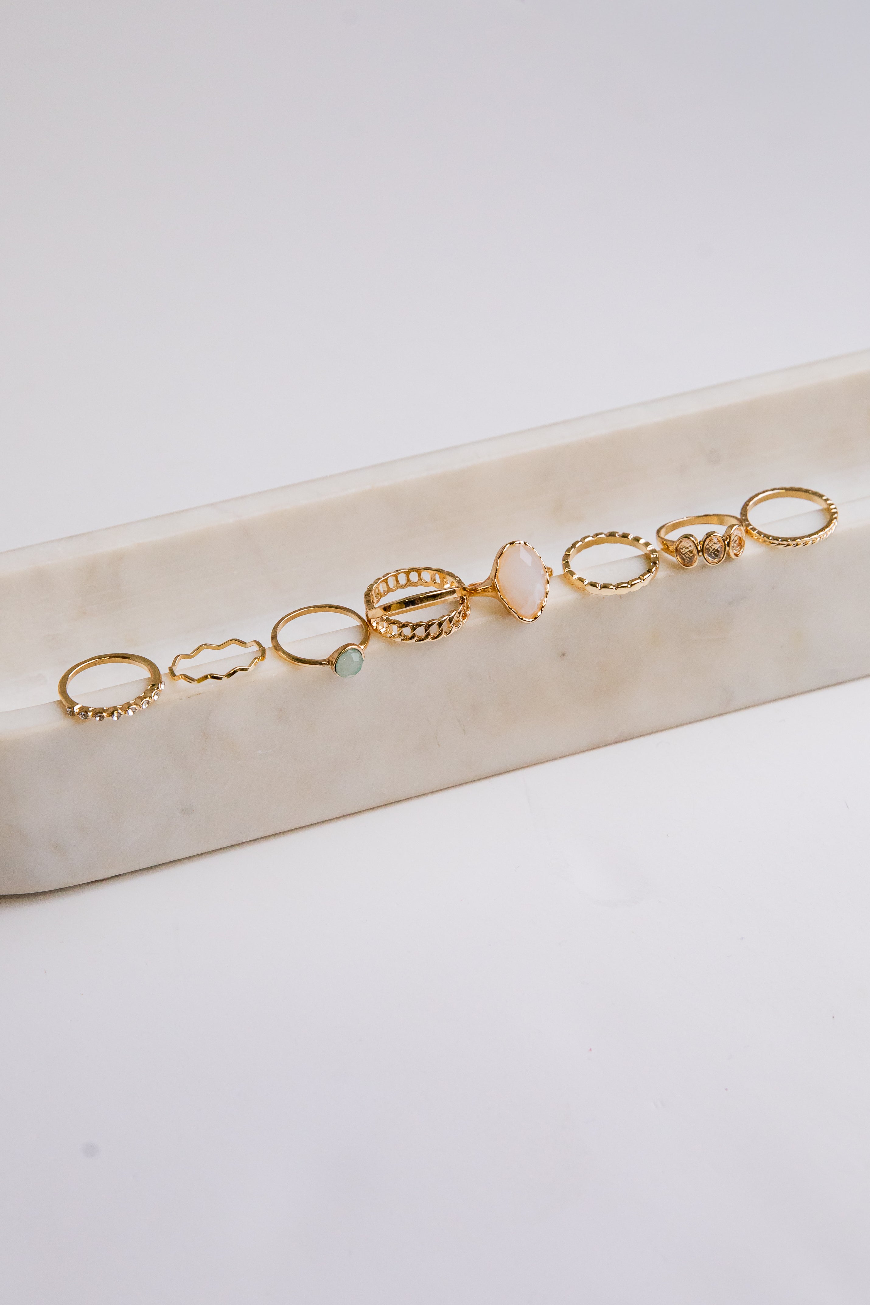 Set of gold rings on a marble surface with a white background