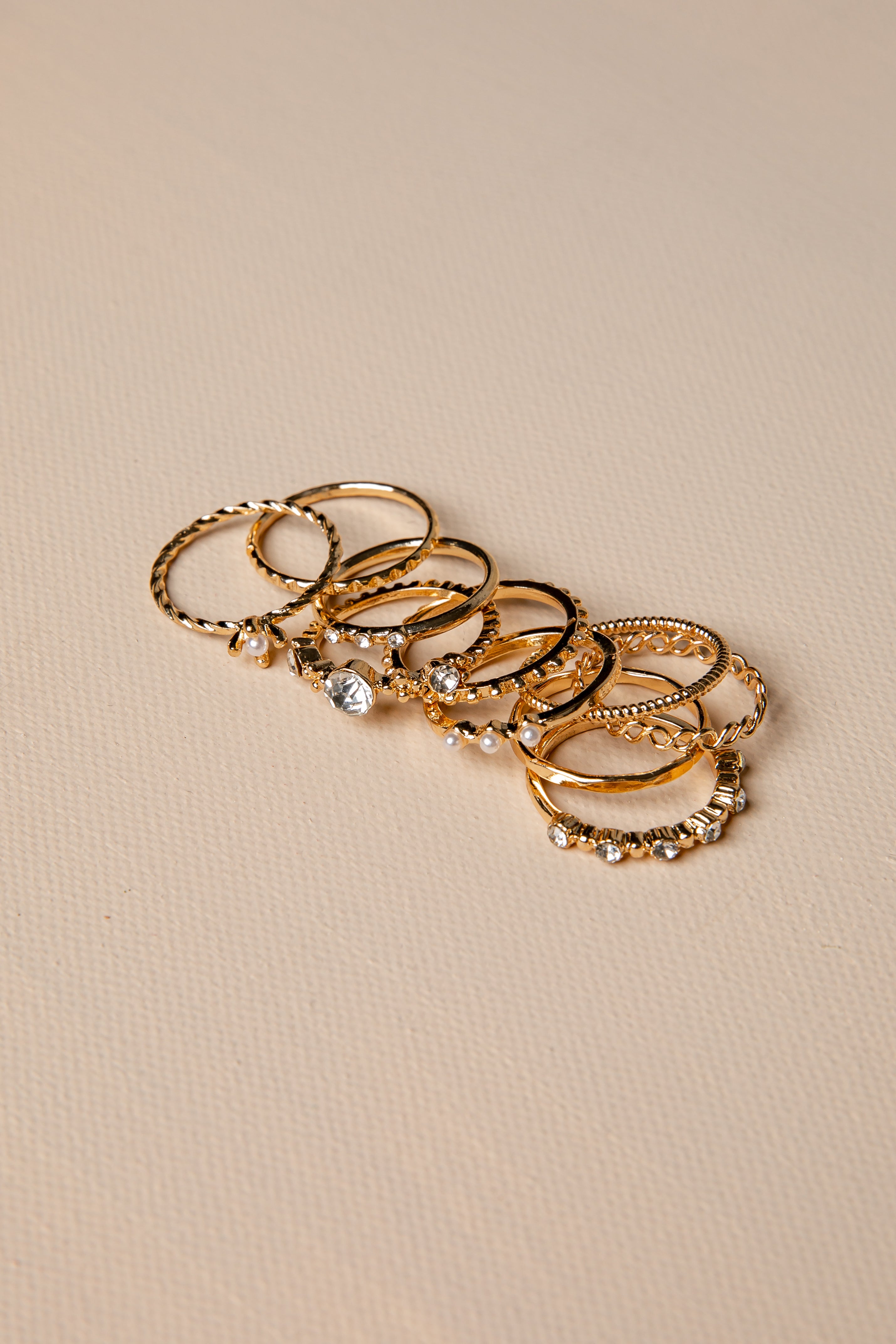 Set of gold rings with various designs on a beige background