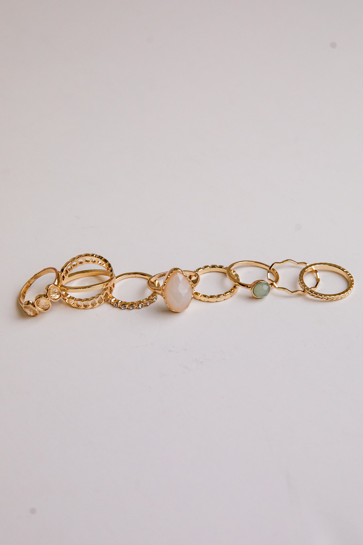 Gold bracelet with three beads on a light gray background