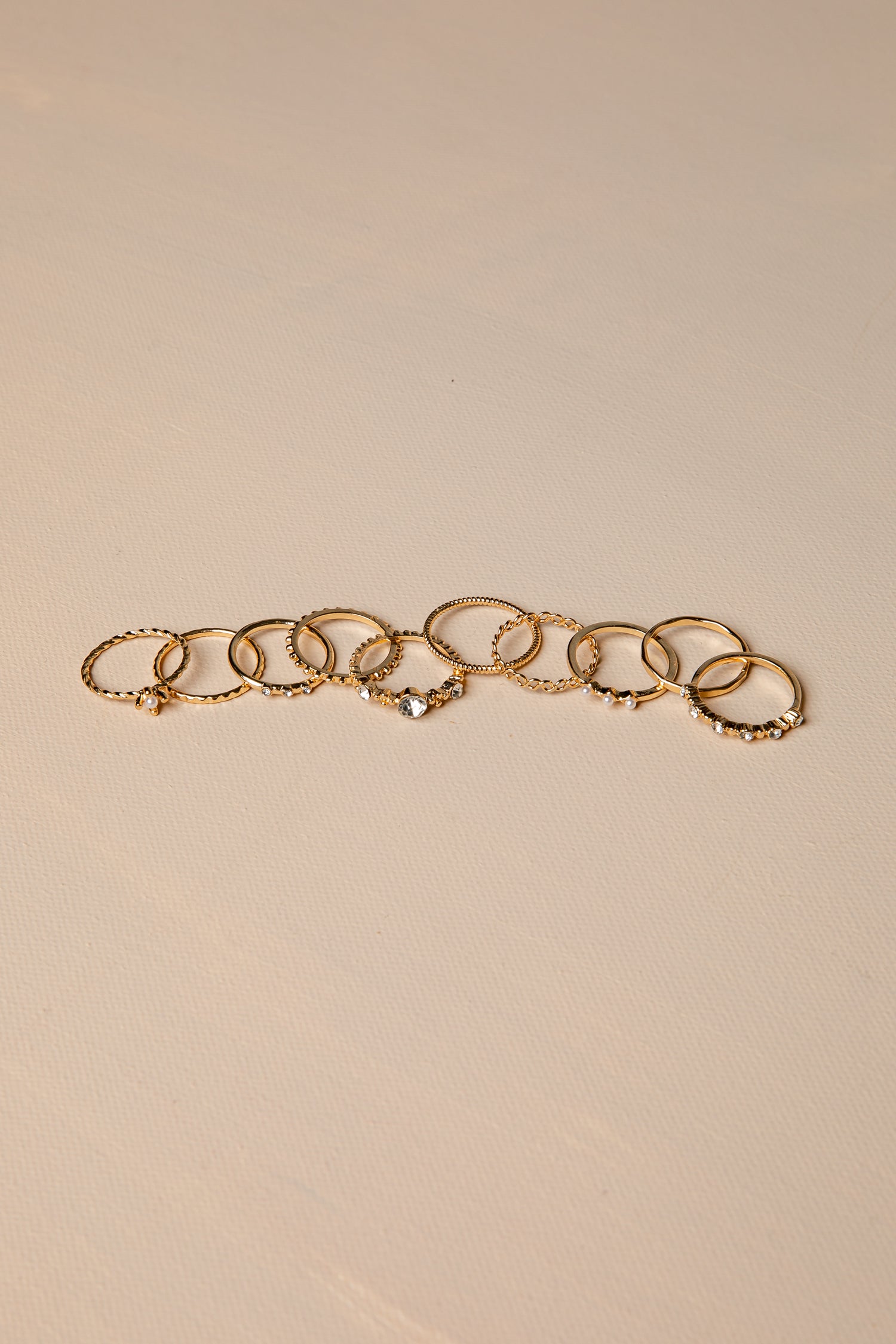 Gold rings with multiple rings on a beige background