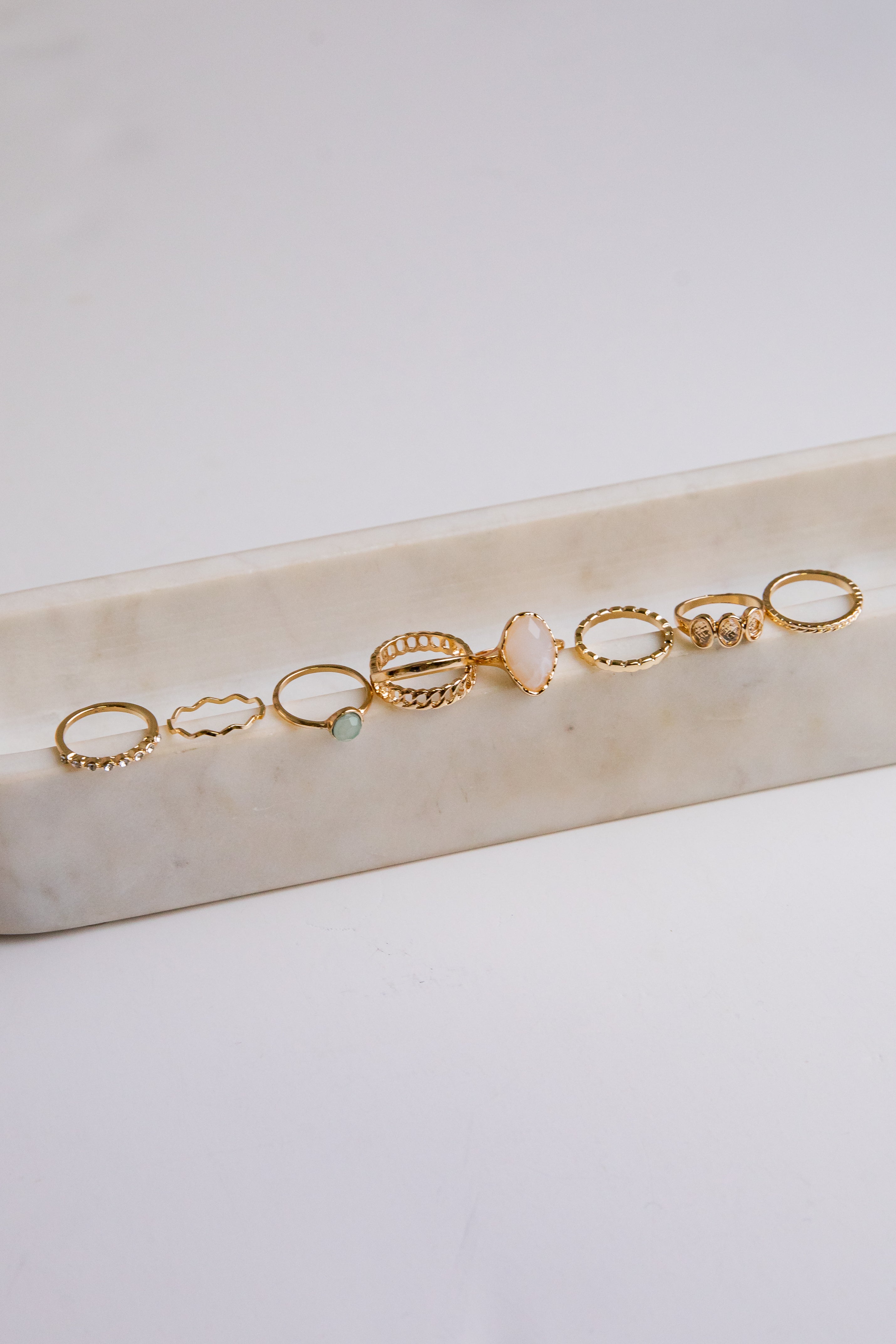 Set of gold rings on a marble surface with a light background