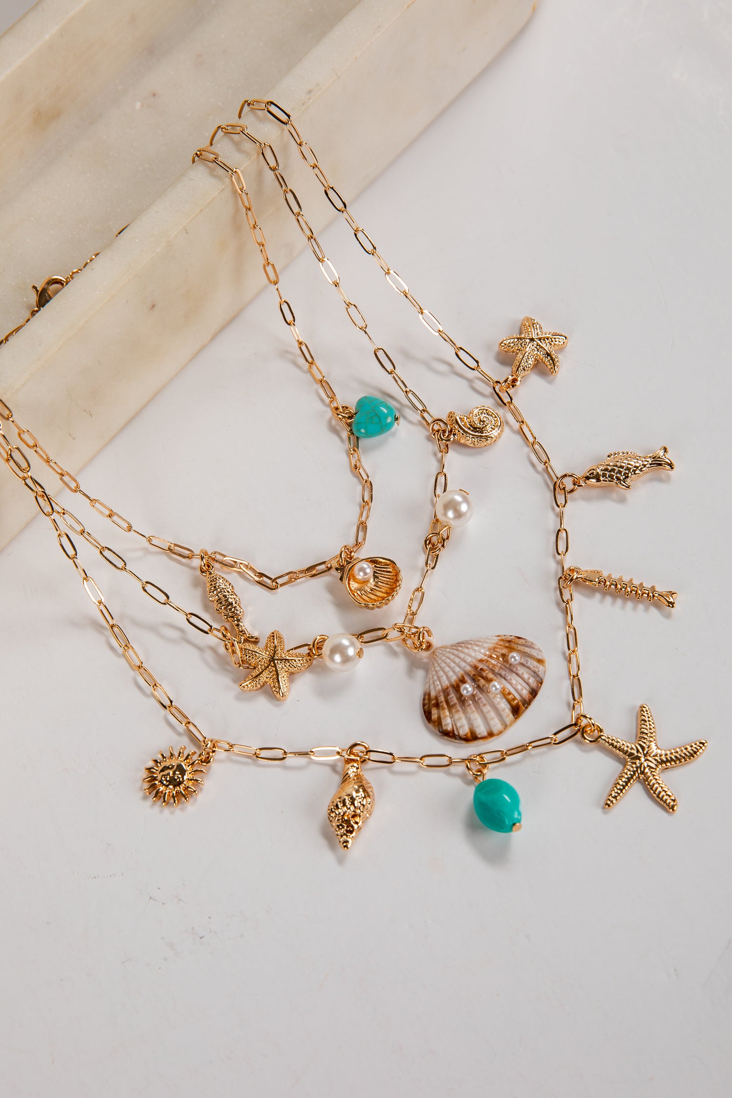 Gold necklaces with various charms on a light background