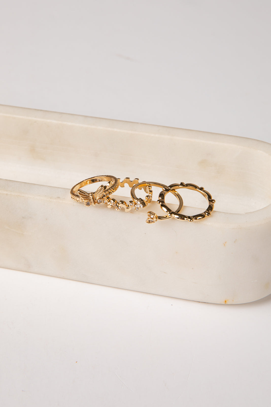 Gold ring with a heart design on a white stone surface