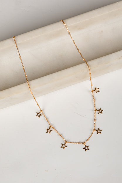 Gold star necklace on a light wooden surface