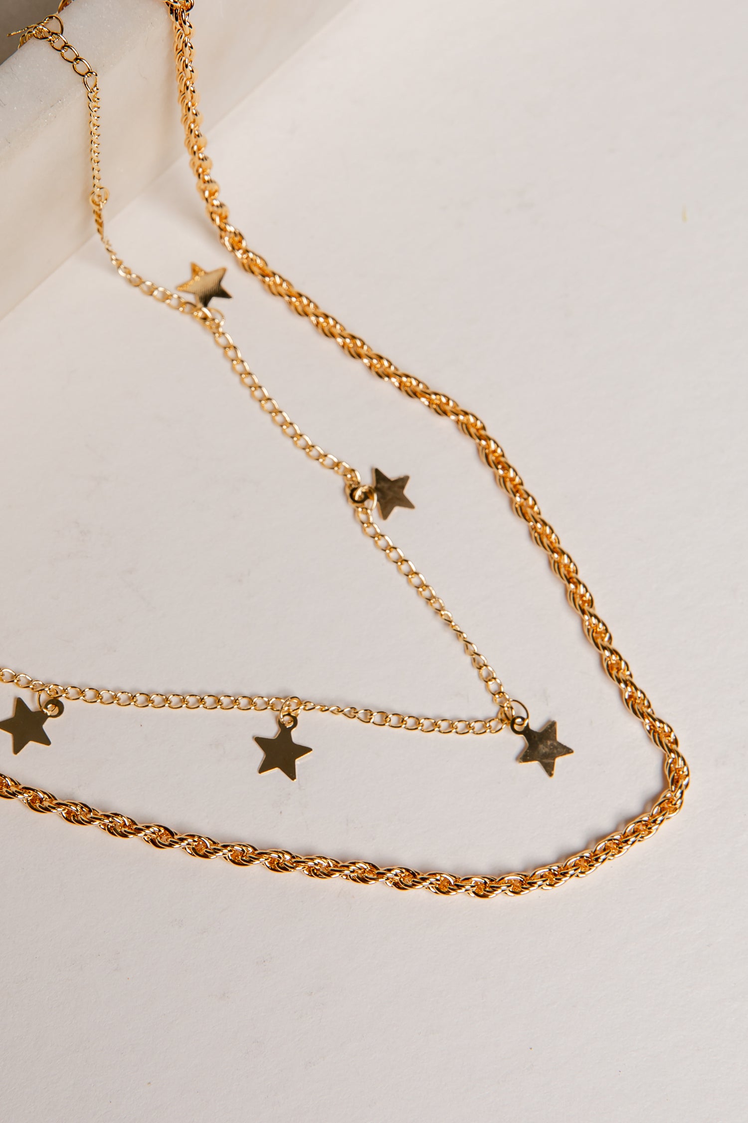 Gold chain necklace with star pendants on a light background