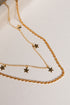 Gold chain necklace with star pendants on a light background