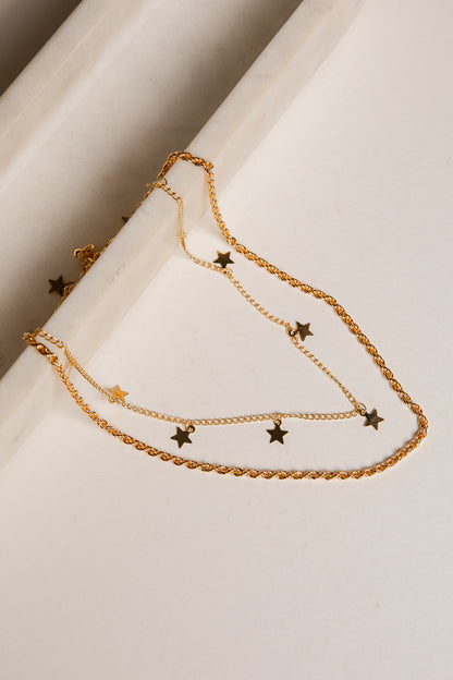 Gold chain necklace with star pendants on a white surface