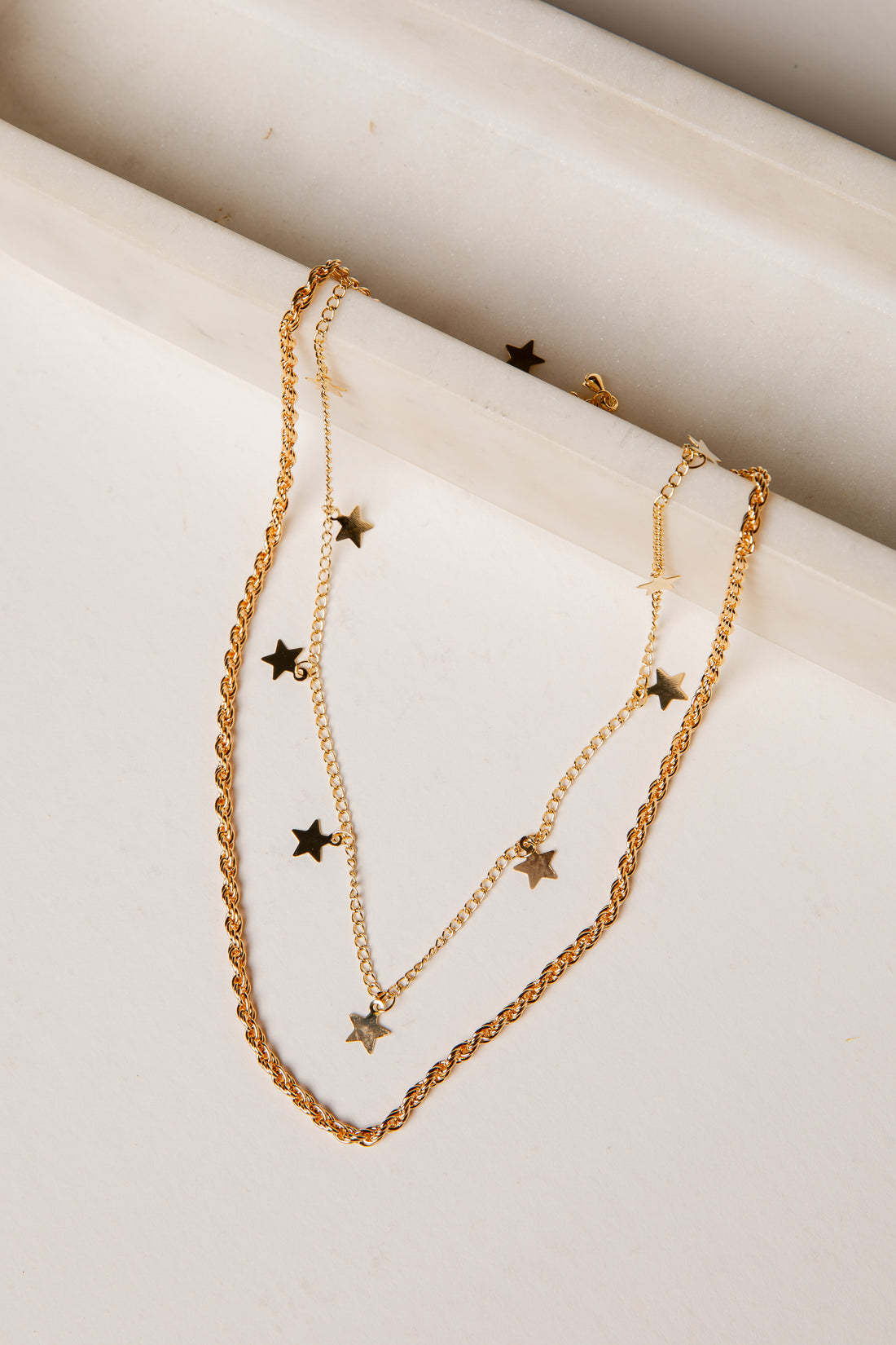 Gold necklace with star pendants on a marble surface