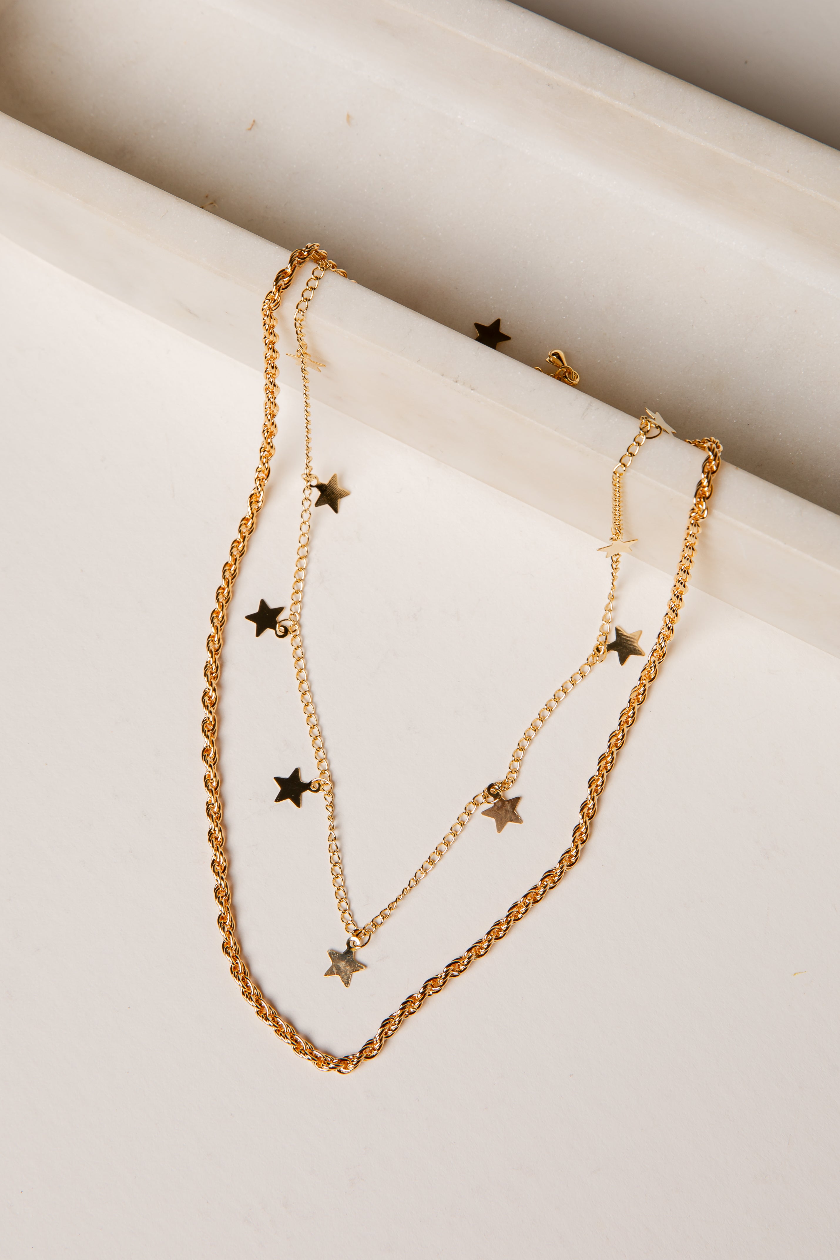 Gold necklace with star pendants on a marble surface