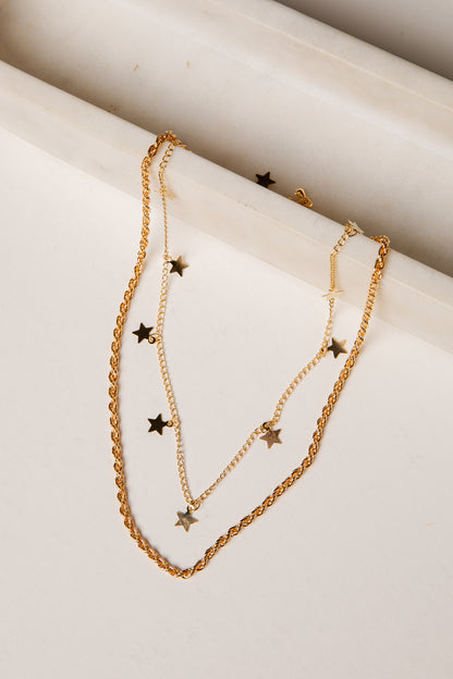 Gold necklace with star pendants on a marble surface